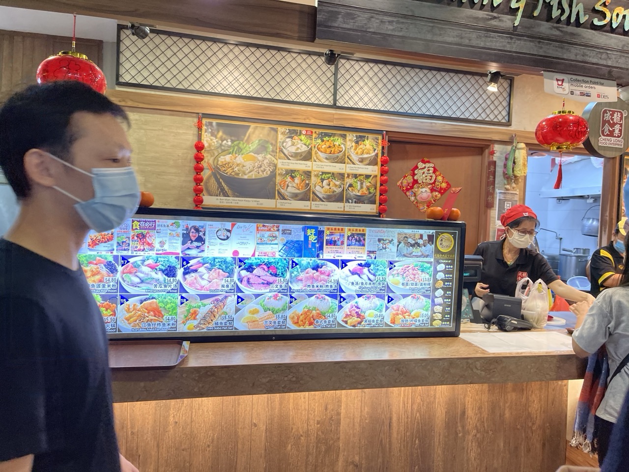 Customer buying food at a fish soup and rice stall in the Waterway Point food court.