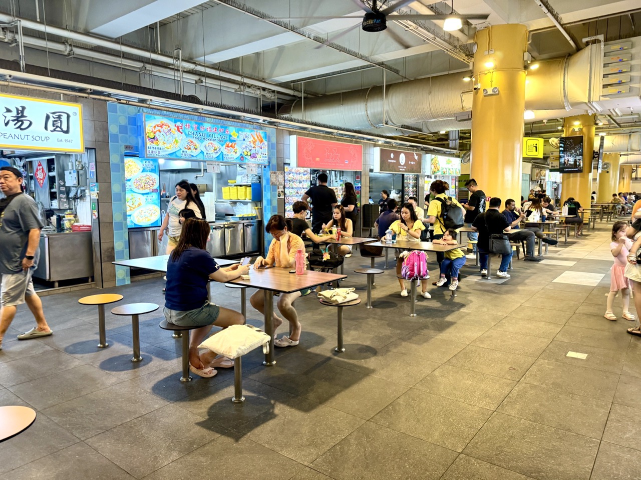 Customers queuing, ordering and collecting food in One Punggol Hawker Centre's Level 2 dining area.