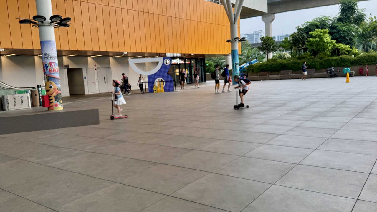 Children riding scooters in the open public area of One Punggol community hub.