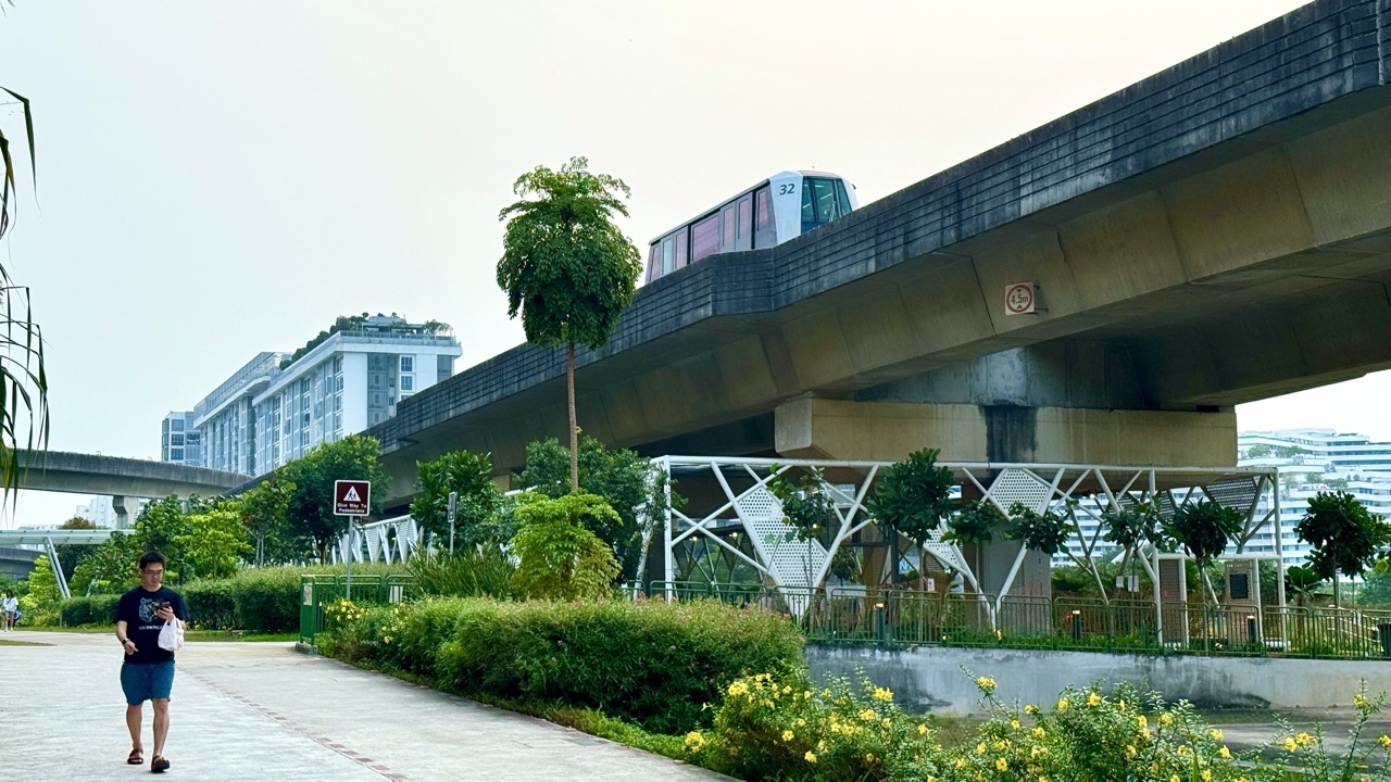 LRT train moving along elevated tracks near Sam Kee station above basketball courts.