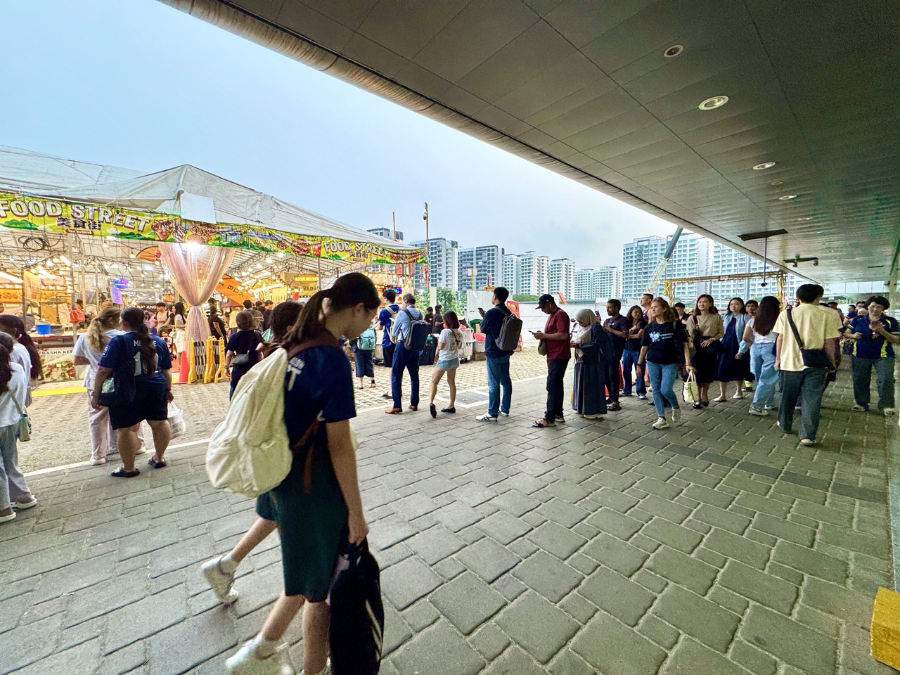 Long queue for nasi biryani at a Punggol night market, with students and pedestrians in the foreground.