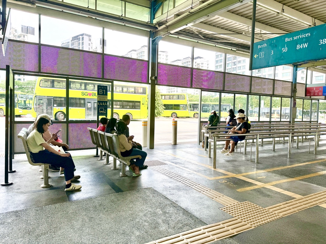 Passengers waiting beside railings and seats at Punggol Temporary Bus Terminal.